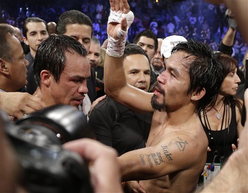 Manny Pacquiao, from the Philippines, right, stands in the ring with Juan Manuel Marquez, from Mexico, after losing by a knockout in their WBO world welterweight  fight Saturday, Dec. 8, 2012, in Las Vegas. (AP Photo/Julie Jacobson)