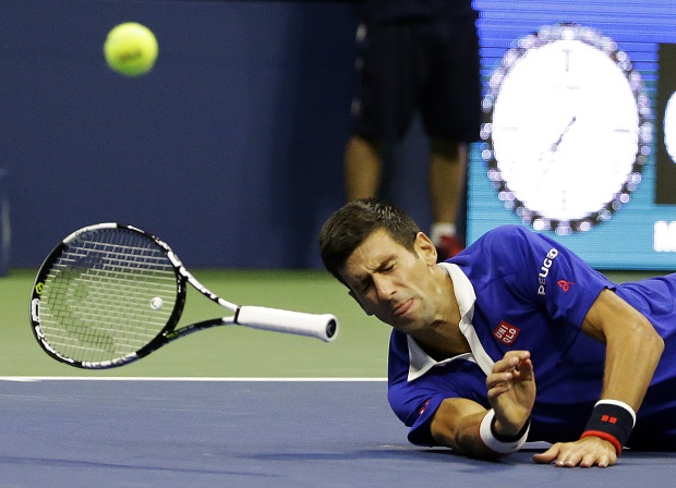 Novak Djokovic, of Serbia, falls to the court while trying to return a shot to Roger Federer, of Switzerland, during the men's championship match of the U.S. Open tennis tournament, Sunday, Sept. 13, 2015, in New York. (AP Photo/David Goldman)
