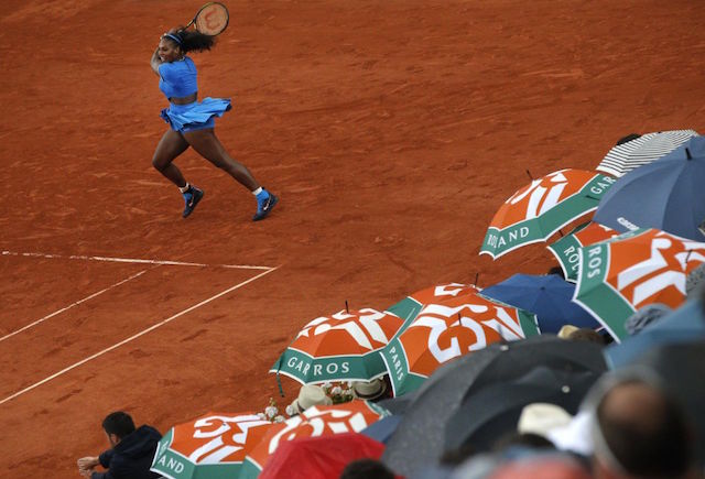 Spectators shield themselves from the rain as Serena Williams of the U.S. returns in the third round match of the French Open tennis tournament against France's Kristina Mladenovic at the Roland Garros stadium in Paris, France, Saturday, May 28, 2016. AP