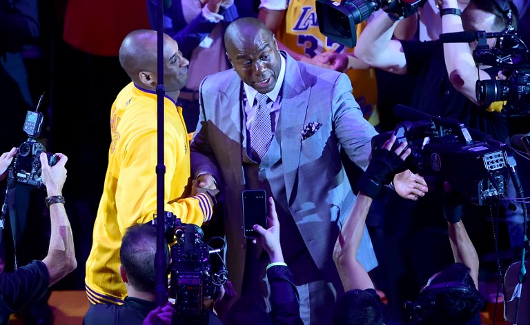 Kobe Bryant of the Los Angeles Lakers reacts meets with Magic Johnson who spoke to the crowd ahead of Kobe's last game for the Lakers against  the Utah Jazz in their season-ending NBA western division matchup n Los Angeles, California on April 13, 2016. / AFP PHOTO / FREDERIC J. BROWN