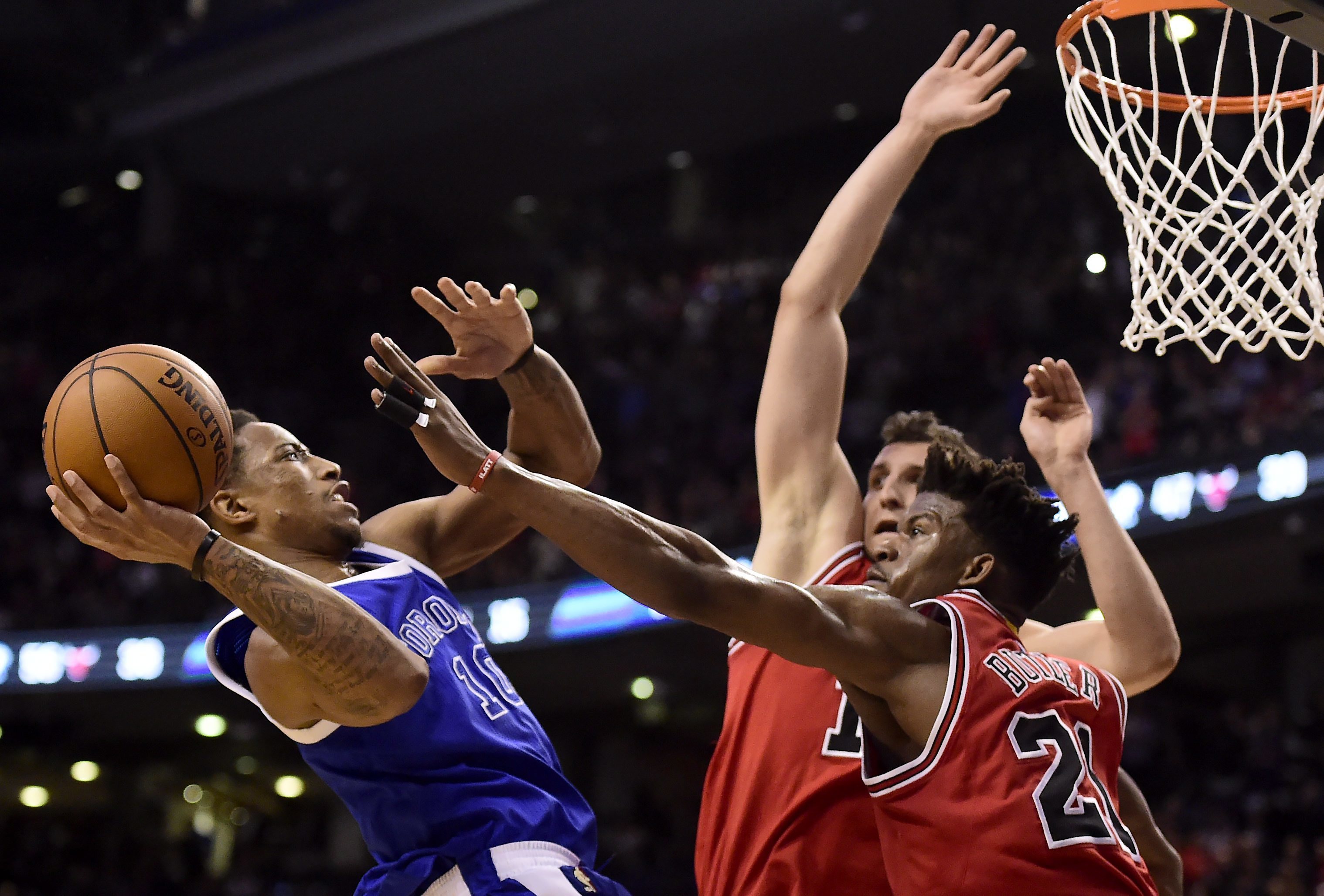Toronto Raptors guard DeMar DeRozan (10) drives to the net to set up teammate Patrick Patterson (54) as Chicago Bulls forward Jimmy Butler (21) and forward Paul Zipser (16) defend during overtime of an NBA basketball game in Toronto, Tuesday, March 21, 2017. (Frank Gunn/The Canadian Press via AP)