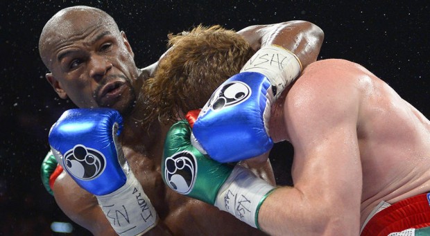 In this photo taken Saturday, September 14, 2013, Floyd Mayweather Jr. gets tangled up with Canelo Alvarez during a world light middleweight title fight in Las Vegas. AP