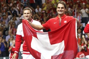 Roger Federer, right, of Switzerland, celebrates next to his teammate Marco Chiudinelli, left, with a Swiss flag after winning against  Italy,  during  the tennis Davis Cup World Group Semifinal between Switzerland and Italy,   in Geneva, Switzerland, Sunday, Sept. 14, 2014. AP