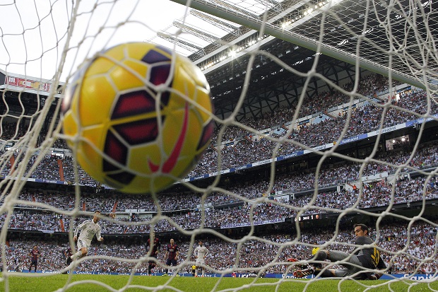 Real Madrid's Cristiano Ronaldo, left, scores his goal during a Spanish La Liga soccer match between Real Madrid and FC Barcelona at the Santiago Bernabeu stadium in Madrid, Spain, Saturday, Oct. 25, 2014.  AP