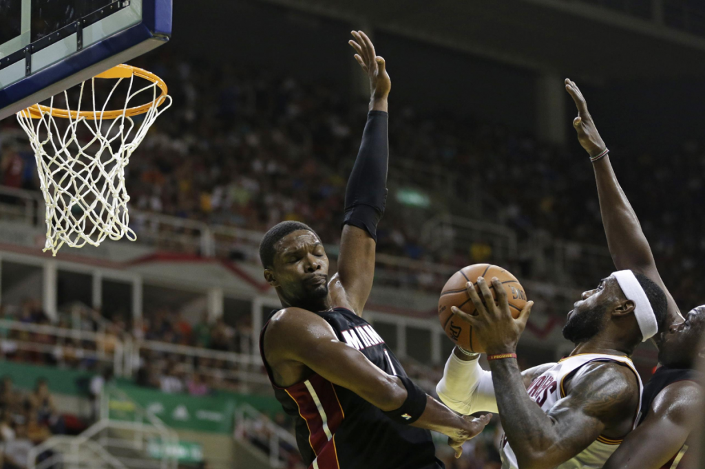 Cleveland Cavaliers' LeBron James, second from right, is blocked by Miami Heat's Chris Bosh, left, and Luol Deng at a NBA preseason basketball game that's part of the NBA Global Games, in Rio de Janeiro, Brazil, Saturday, Oct. 11, 2014. AP