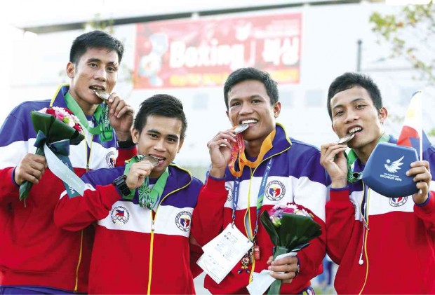 Silver medalist Charly Suarez (third from left) and bronze-medal winners (from left) Wilfredo Lopez, Mark Anthony Barriga and Mario Fernandez bite their medals outside the Asian Games boxing venue in Incheon. NIÑO JESUS ORBETA