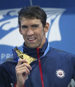 In an Aug. 23, 2014, file photo Michael Phelps of the U.S. holds up his men's 100m butterfly gold medal at the Pan Pacific swimming championships in Gold Coast, Australia. USA Swimming on Monday , Oct. 6, 2014, suspended Phelps for six months as a result of the Olympic champion's second DUI arrest. AP 