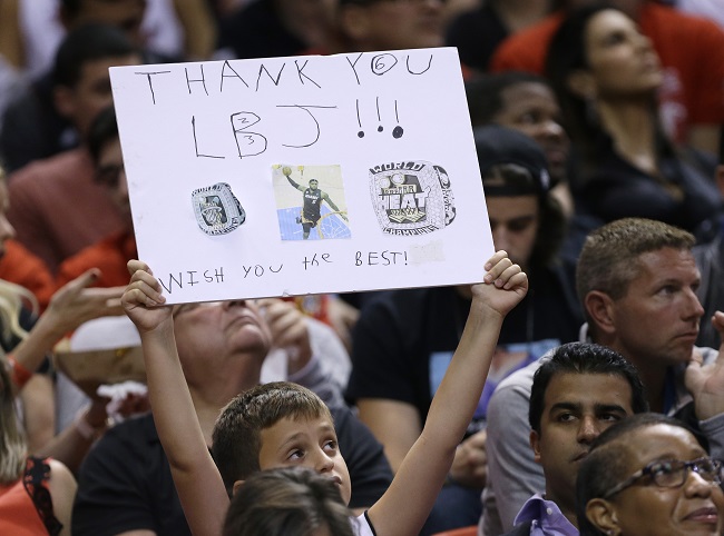 A boy holds up a sign thanking Cleveland Cavaliers' LeBron James for his time played with the Miami Heat during the second half of an NBA basketball game between the Heat and the Cavaliers, Thursday, Dec. 25, 2014, in Miami. The Heat defeated the Cavaliers 101-91. AP
