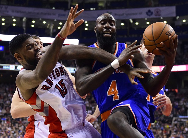 Toronto Raptors' Amir Johnson (15) and New York Knicks' Quincy Acy (4) scramble for the ball during first-half NBA basketball game action in Toronto, Sunday, Dec. 21, 2014. AP