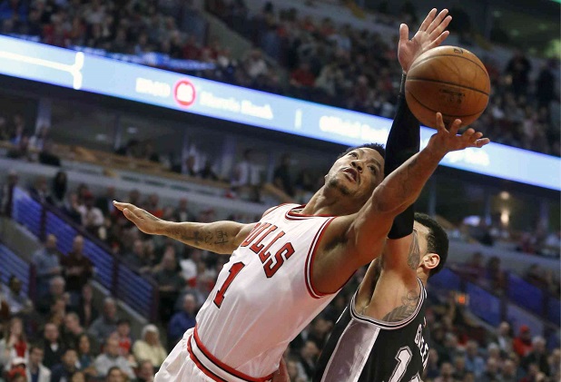 BULLS star Derrick Rose (left) stretches for a layup against Spurs guard Danny Green. AP