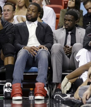 Miami Heat Dwyane Wade, left, and Luol Deng (9) watch their teammates play against the Dallas Mavericks from the bench in the second half of an NBA basketball  game in Miami, Friday, Jan. 30, 2015. The Mavericks won 93-72. (AP Photo/Alan Diaz)