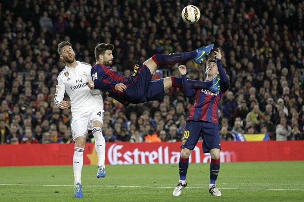 Barcelona's Gerard Pique kicks the ball with Real Madrid's Sergio Ramos, left, and Barcelona's Lionel Messi, right, during a Spanish La Liga soccer match between FC Barcelona and Real Madrid at Camp Nou stadium, in Barcelona, Spain, Sunday, March 22, 2015. (AP Photo/Emilio Morenatti)