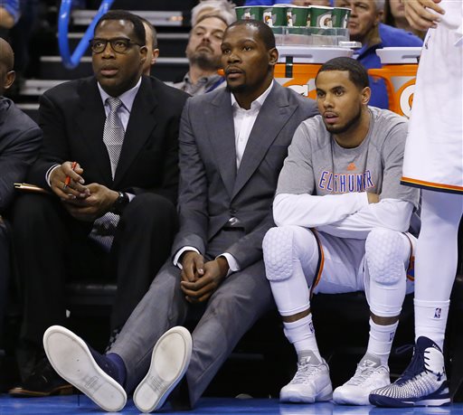 FILE - In this March 4, 2015, file photo, injured Oklahoma City Thunder forward Kevin Durant, center, watches from the bench with guard D.J. Augustin, right, and assistant coach Mark Bryant, left, during the first quarter of an NBA basketball game against the Philadelphia 76ers in Oklahoma City. Durant will have bone graft surgery next week to deal with a fractured bone in his right foot, and he will miss the rest of the season, the Oklahoma City Thunder announced Friday, March 27, 2015. AP PHOTO