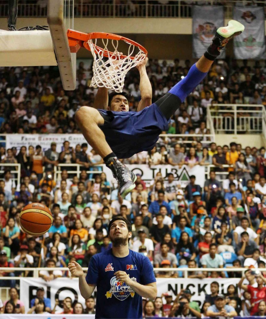 REY GUEVARRA, with Meralco teammate Simon Atkins underneath, hangs on to the rim on his way to winning the Slam Dunk contest.  MARIANNE BERMUDEZ