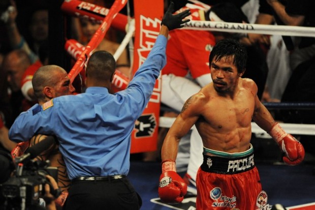 Manny Pacquiao (R) of the Philippines watches as the referee consults with Miguel Angel Cotto of Puerto Rico (L) and stops the fight in their WBO Welterweight Championship fight at the MGM Grand Garden Arena on November 14, 2009 in Las Vegas, Nevada.  Pacquiao won his seventh world title in as many divisions and what amazes boxing experts is he hasn't show any signs of losing power as he fights bigger stronger opponents. Pacquiao's six titles came in a half dozen weight classes ranging from 112 to 140 pounds. He weighed just 106 pounds in his pro debut in 1995 and captured his first title in the 112-pound flyweight division.         AFP PHOTO/Mark RALSTON