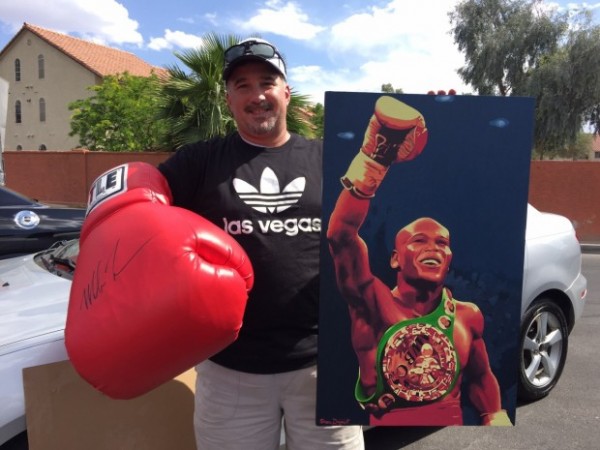 Tom Diana, wearing a giant glove autographed by Mike Tyson, also brings a painting of Floyd Mayweather Jr. made by his friend.