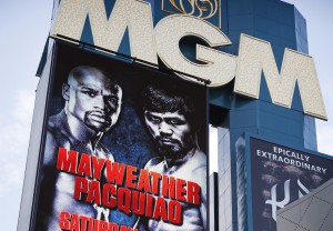 People ride an escalator with a sign advertising the Mayweather Pacquiao fight towering over them at the MGM Grand Wednesday, April 22, 2015, in Las Vegas. (AP Photo/John Locher)