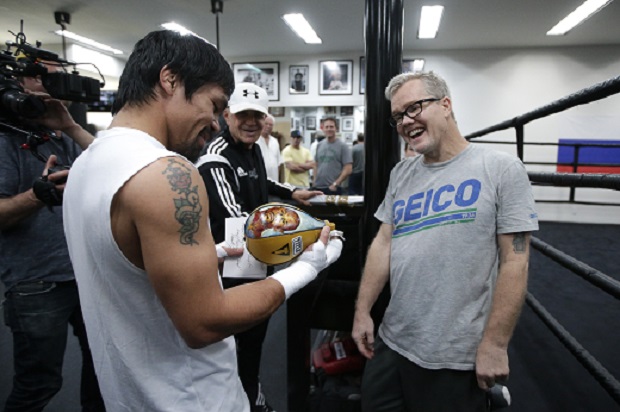 Boxer Manny Pacquiao, left, of the Philippines, and his trainer Freddie Roach share a laugh as they look at a speed bag showing an images of Floyd Mayweather Jr., a gift from lawyer Robert Shapiro, background center, Monday, April 13, 2015, in Los Angeles. Pacquiao will face Mayweather Jr. in a welterweight boxing match in Las Vegas on May 2. (AP Photo/Jae C. Hong)
