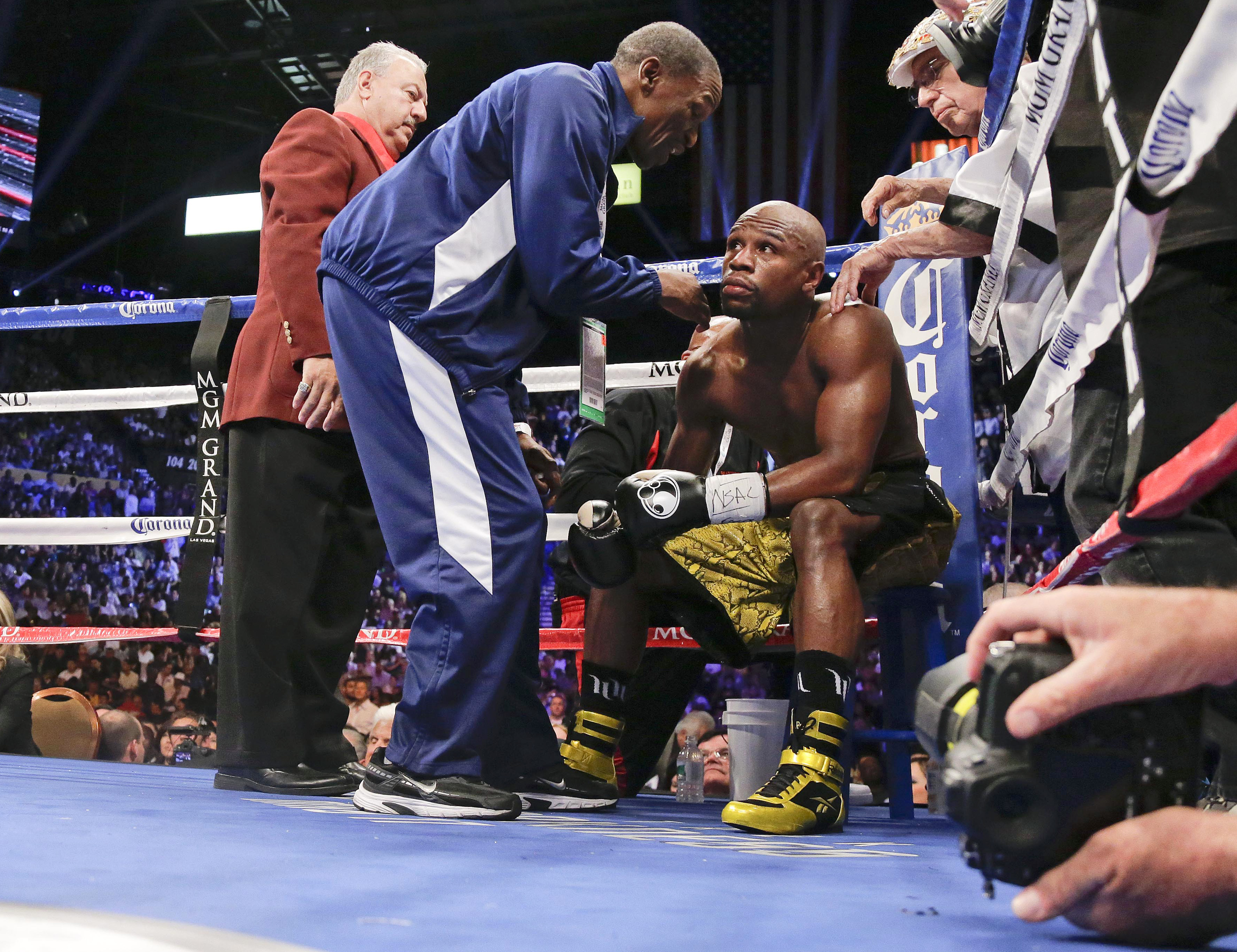 FILE - In this May 4, 2013, file photo, Floyd Mayweather Jr., right, listens to his father and trainer Floyd Mayweather Sr. after the third round against Robert Guerrero during a WBC welterweight title fight,  in Las Vegas. He taught his son to throw punches before he could walk, and he'll be in his corner for the biggest fight of his life against Manny Pacquiao on May 2. The relationship betwee Mayweather Sr. and his son, though, hasn't always been good. (AP Photo/Rick Bowmer, File)