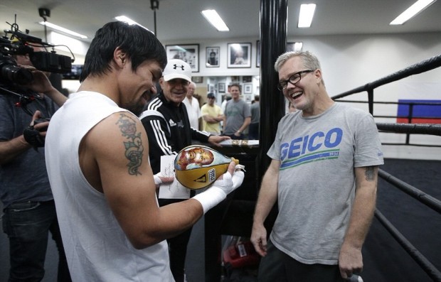 Caption: Manny Pacquiao and Hall of Fane trainer Freddie Roach laugh at the custom-made speed ball that has Floyd Mayweather's face on it. AP