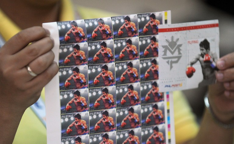 A post office employee shows commemorative stamps of Philippine boxing icon Manny Pacquiao in Manila on April 21, 2015. Manny Pacquiao's face is on shirts, dolls and postage stamps, his life story is playing in movie houses and millions are getting ready to party as the Philippine boxing hero's "fight of the century" nears.  AFP PHOTO/JAY DIRECTO 