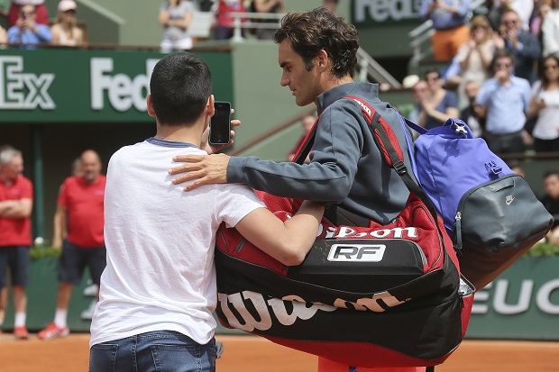 A boy who climbed down from the stands takes a selfie with Switzerland's Roger Federer in the first round match of the French Open tennis tournament against Colombia's Alejandro Falla at the Roland Garros stadium, in Paris, France, Sunday, May 24, 2015. (AP Photo/David Vincent)