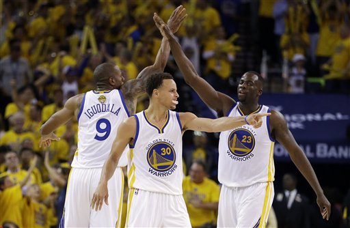 Golden State Warriors guard Stephen Curry, center, forward Andre Iguodala (9) and forward Draymond Green, right, react during the second half of Game 5 of basketball's NBA Finals against the Cleveland Cavaliers in Oakland, Calif., Sunday, June 14, 2015. AP PHOTO