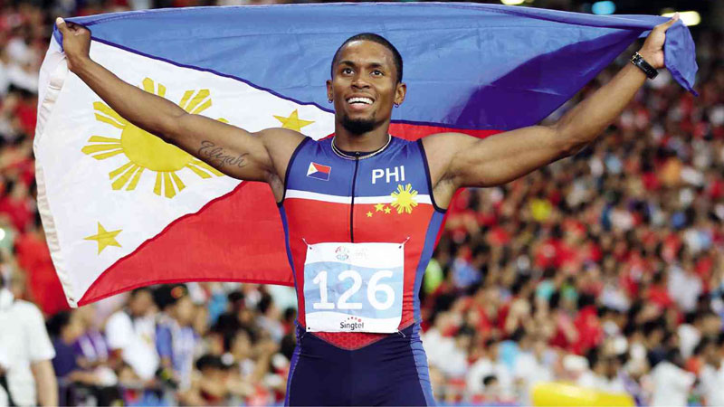 SPRINT CHAMP Eric Shauwn Cray carries the Philippine flag around the track after winning the men’s 100-meter run, the centerpiece event in athletics, at the 28th Southeast Asian Games in Singapore. Cray completed a sprint double for the Philippines on Tuesday after Kayla Anise Richardson, another Fil-Am, ruled the women’s century. RAFFY LERMA
