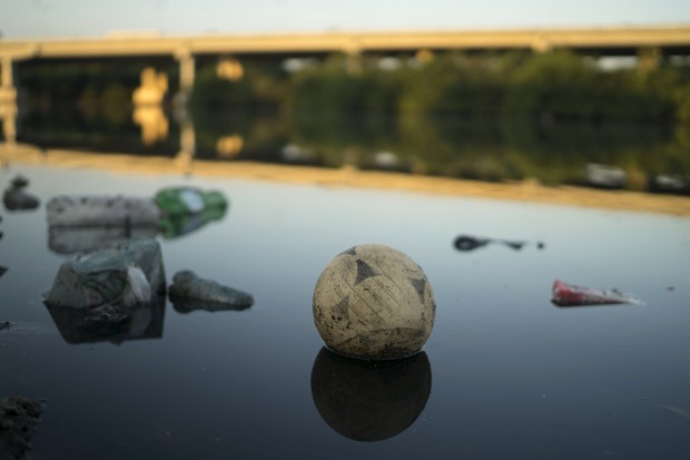 A discarded ball floats on the water in a canal at the Mare slum complex  in Rio de Janeiro, Brazil, Friday, July 31, 2015. In Rio, much of the waste runs through open-air ditches to fetid streams and rivers that feed the Olympic water sites and blight the city's picture postcard beaches. (AP Photo/Leo Correa)