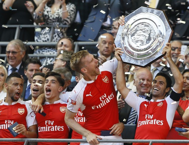 Arsenal's captain Per Mertesacker, second right, holds the trophy with Mikel Arteta, right, after winning the English Community Shield soccer match between Arsenal and Chelsea at Wembley Stadium in London, Sunday, Aug. 2, 2015. Arsenal won the match 1-0. (AP Photo/Kirsty Wigglesworth)