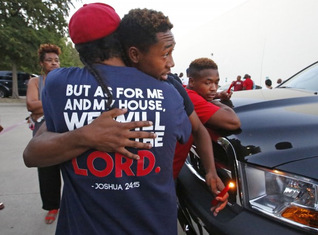 People comfort on another at the candlelight vigil for Christian Taylor, held in the parking lot of Koinonia Christian Church in Arlington, Texas, Saturday, Aug. 8, 2015. The FBI has been asked to help investigate the death of Taylor, a Texas college football player, who was fatally shot by an officer during a burglary call at a car dealership, a suburban Dallas police chief said Saturday. (Louis DeLuca/The Dallas Morning News via AP) MANDATORY CREDIT; MAGS OUT; TV OUT; INTERNET USE BY AP MEMBERS ONLY; NO SALES
