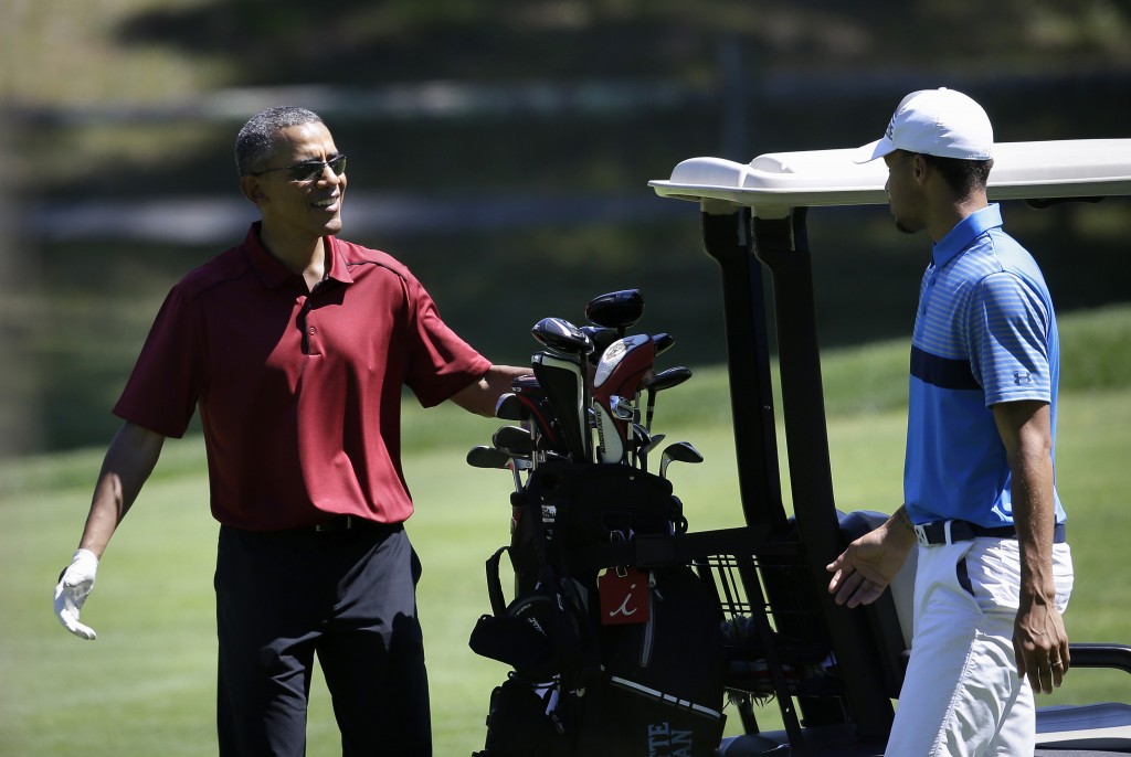 President Barack Obama speaks with NBA basketball player Stephen Curry, of the Golden State Warriors, while golfing, Friday, Aug. 14, 2015, at Farm Neck Golf Club, in Oak Bluffs, Mass., on the island of Martha's Vineyard. The president, first lady Michelle Obama, and daughter Sasha are vacationing on the island. (AP Photo/Steven Senne)