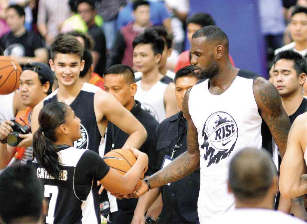 James hands over an autographed ball to a cagebelle as teenaged Filipino cage star Kobe Paras looks on. AUGUST DELA CRUZ