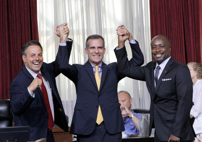 Councilman Joe Buscaino, left, with Los Angeles Mayor Eric Garcetti, center, and Councilman Marqueece Harris-Dawson celebrate after a city council vote in Los Angeles on Tuesday, Sept. 1, 2015. AP