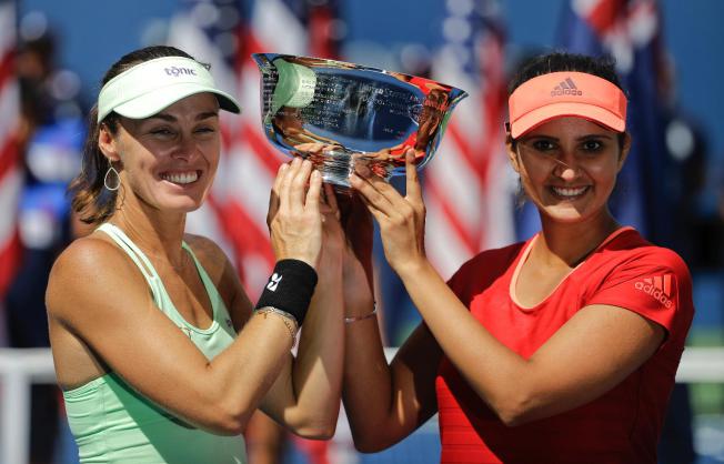 Martina Hingis and Sania Mirza hold up the U.S. Open women’s doubles championship trophy. AP