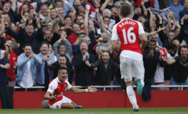 Arsenal's Alexis Sanchez, left, looks round as he celebrates with teammates after scoring his second goal of the game during the English Premier League soccer match between Arsenal and Manchester United at Emirates stadium in London, Sunday, Oct. 4, 2015.(AP Photo/Frank Augstein)