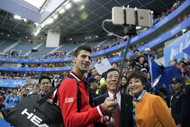 Novak Djokovic of Serbia, center, takes a selfie with officials after winning his men's singles match against Zhang Ze of China in the China Open tennis tournament at the National Tennis Stadium in Beijing, Thursday, Oct. 8, 2015. (AP Photo/Andy Wong)