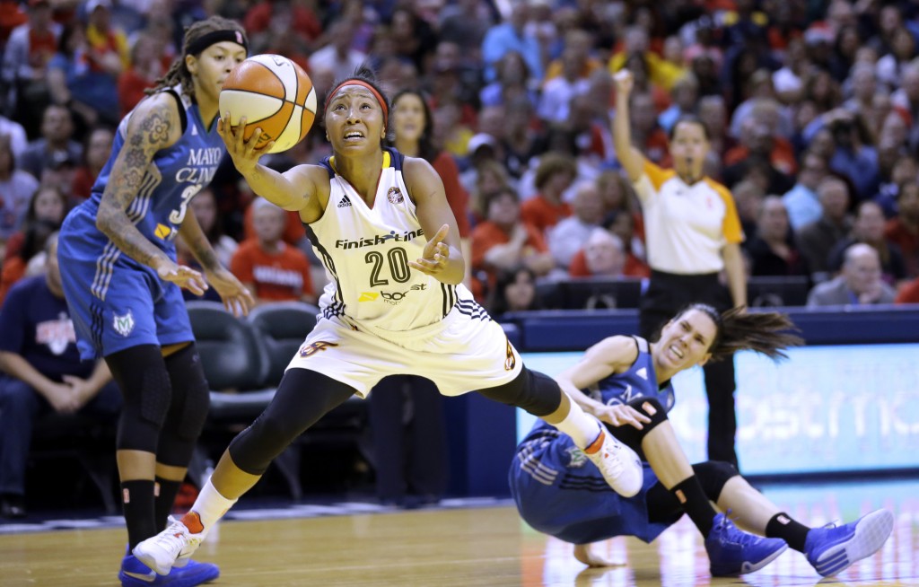 Indiana Fever's Briann January, center, heads to the basket as Minnesota Lynx's Seimone Augustus, left, and Anna Cruz, right, watch in the first half of Game 4 of the WNBA Finals basketball series, in Indianapolis, Sunday, Oct. 11, 2015.  (AP Photo/Michael Conroy)