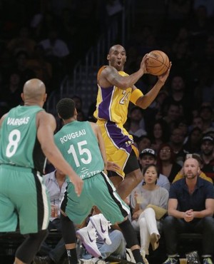 Los Angeles Lakers' Kobe Bryant, top, passes the ball as Maccabi Haifa’s Rene Rougeau looks on during the first half of an NBA preseason basketball game, Sunday, Oct. 11, 2015, in Los Angeles. (AP Photo/Jae C. Hong)