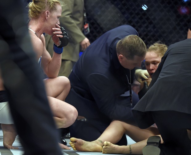Holly Holm, left, watches Ronda Rousey, right, being tended after knocking her out during their UFC 193 bantamweight title fight in Melbourne, Australia, Sunday, Nov. 15, 2015. Holm pulled off a stunning upset victory over Rousey in the fight, knocking out the women's bantamweight champion in the second round with a powerful kick to the head Sunday. (AP Photo/Andy Brownbill)