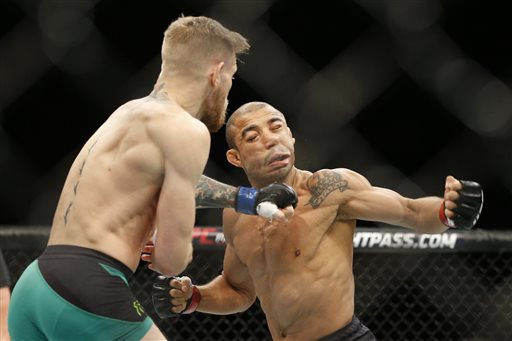 Conor McGregor, left, fights Jose Aldo during a featherweight championship mixed martial arts bout at UFC 194, Saturday, Dec. 12, 2015, in Las Vegas. McGregor stopped Aldo with one spectacular punch just 13 seconds into the first round Saturday night, backing up his bravado and claiming the undisputed featherweight title at UFC 194 on Saturday night.  (AP Photo/John Locher)