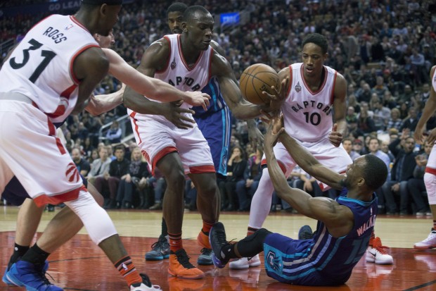Toronto Raptors' Bismack Biyombo, center, grabs a loose ball under the hoop in front of Charlotte Hornets' Kemba Walker, as Raptors' Terrence Ross (31) and DeMar DeRozan (10) look on during the second half of an NBA basketball game in Toronto, Friday, Jan. 1, 2016.  (Chris Young/The Canadian Press via AP) MANDATORY CREDIT