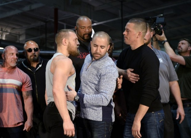 FILE --- UFC featherweight champion Conor McGregor (L) and lightweight contender Nate Diaz (R) are held apart by Dave Sholler (C), UFC vice president of public relations, after a news conference at UFC Gym February 24, 2016, in Torrance, California.   Kevork Djansezian/Getty Images/AFP