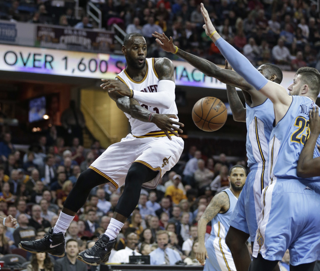 From left to right, Cleveland Cavaliers' LeBron James passes around Denver Nuggets' JaKarr Sampson and Jusuf Nurkic, from Bosnia, in the first half of an NBA basketball game Monday, March 21, 2016, in Cleveland. (AP Photo/Tony Dejak)
