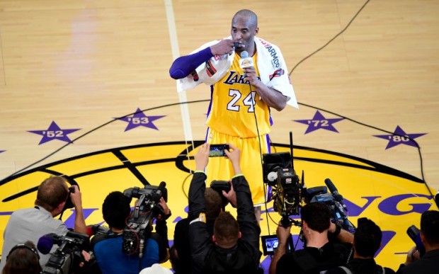 Kobe Bryant (top) of the Los Angeles Lakers reacts while addressing fans following his final game as a Laker in their season-ending NBA western division matchup aginst the Utah Jazz in Los Angeles, California on April 13, 2016, where the Lakers defeated the Jazz 101-96.  / AFP PHOTO / FREDERIC J. BROWN