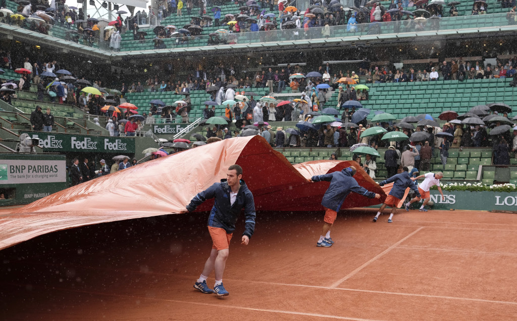 Stadium workers cover the clay court as the fourth round match of the French Open tennis tournament between Japan's Kei Nishikori and France's Richard Gasquet was interrupted because of the rain at the Roland Garros stadium in Paris, France, Sunday, May 29, 2016. (AP Photo/Alastair Grant)
