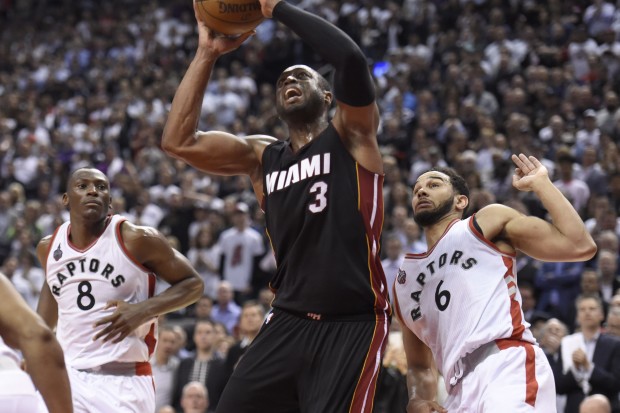 Miami Heat's Dwyane Wade (3) scores as Toronto Raptors' Cory Joseph (6) and Bismack Biyombo (8) defend late in the second half of Game 5 of the NBA basketball Eastern Conference semifinals, Wednesday, May 11, 2016, in Toronto. (Frank Gunn/The Canadian Press via AP)