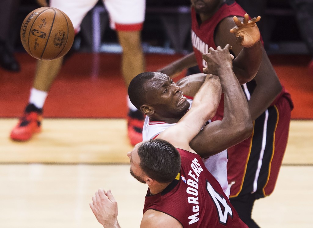 Toronto Raptors center Bismack Biyombo, center, is fouled by Miami Heat forward Josh McRoberts (4) during the second half of Game 7 of the NBA basketball Eastern Conference semifinals in Toronto, Sunday, May 15, 2016. (Nathan Denette/The Canadian Press via AP) MANDATORY CREDIT