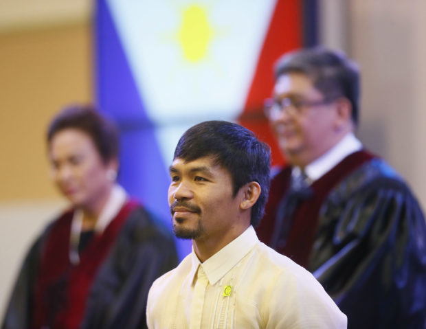With the Philippine National flag in background, Filipino boxing great and now Senator Manny Pacquiao stands while a citation is being read to him during ceremony at the Commission on Elections Thursday, May 19, 2016 in suburban Pasay city south of Manila, Philippines. Pacquiao has won a seat in the Philippine Senate based on an unofficial count bringing him closer to a possible crack at the presidency. Pacquiao said he will retire from boxing to become a full-time politician. (AP Photo/Bullit Marquez)