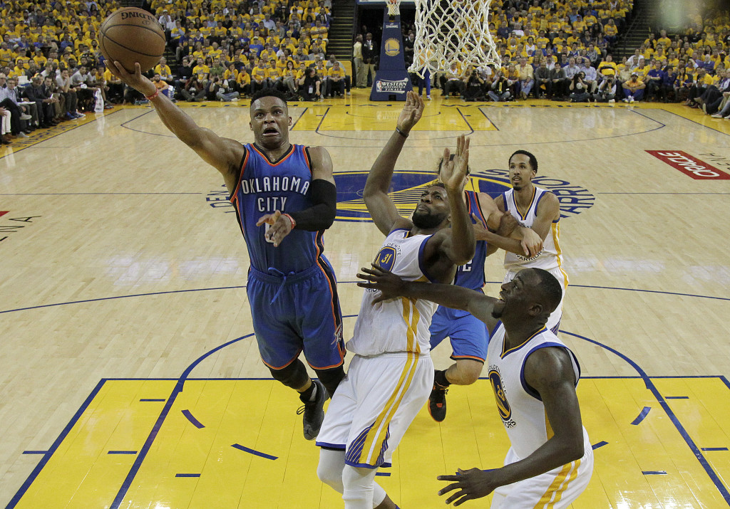 Oklahoma City Thunder guard Russell Westbrook, left, shoots against Golden State Warriors center Festus Ezeli (31) and forward Draymond Green (23) during the second half of Game 1 of the NBA basketball Western Conference finals in Oakland, Calif., Monday, May 16, 2016. The Thunder won 108-102. (AP Photo/Marcio Jose Sanchez)